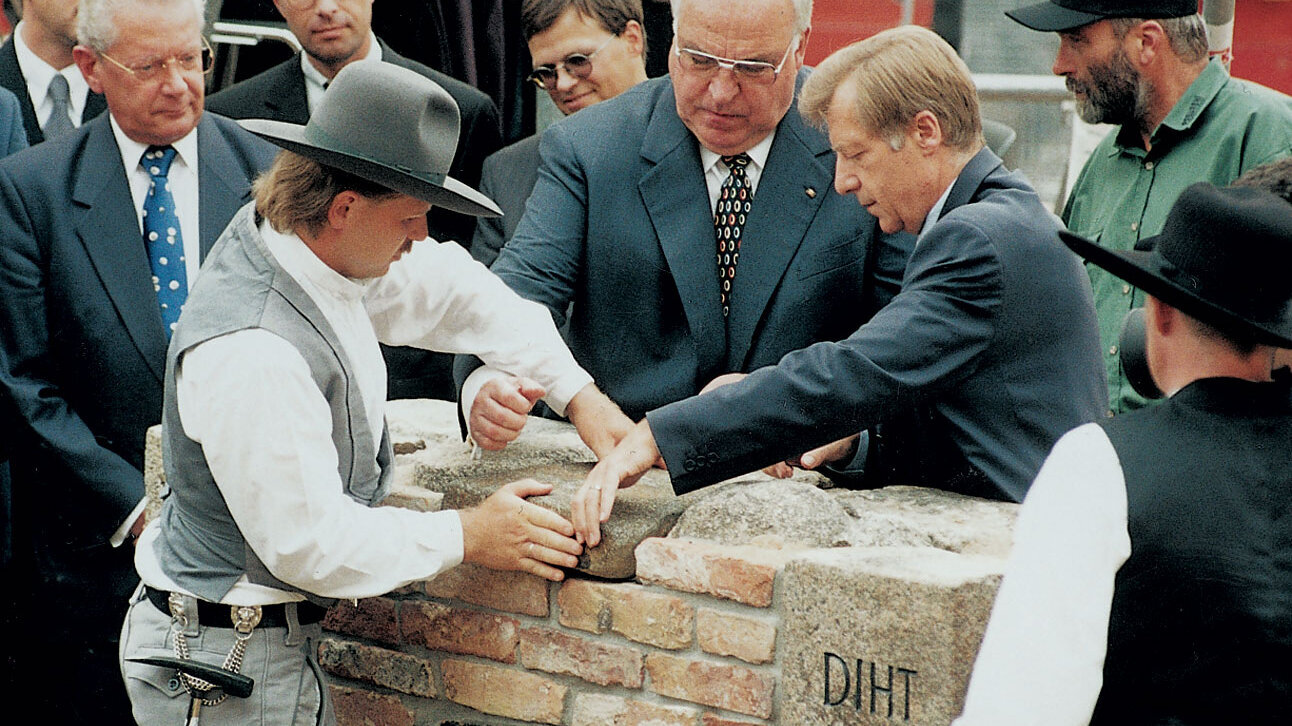 Ceremonial laying of the foundation stone with the participation of craftsmen and politicians, including a brick wall with the abbreviations ‘DIHT’ and ‘BDI’ engraved on it