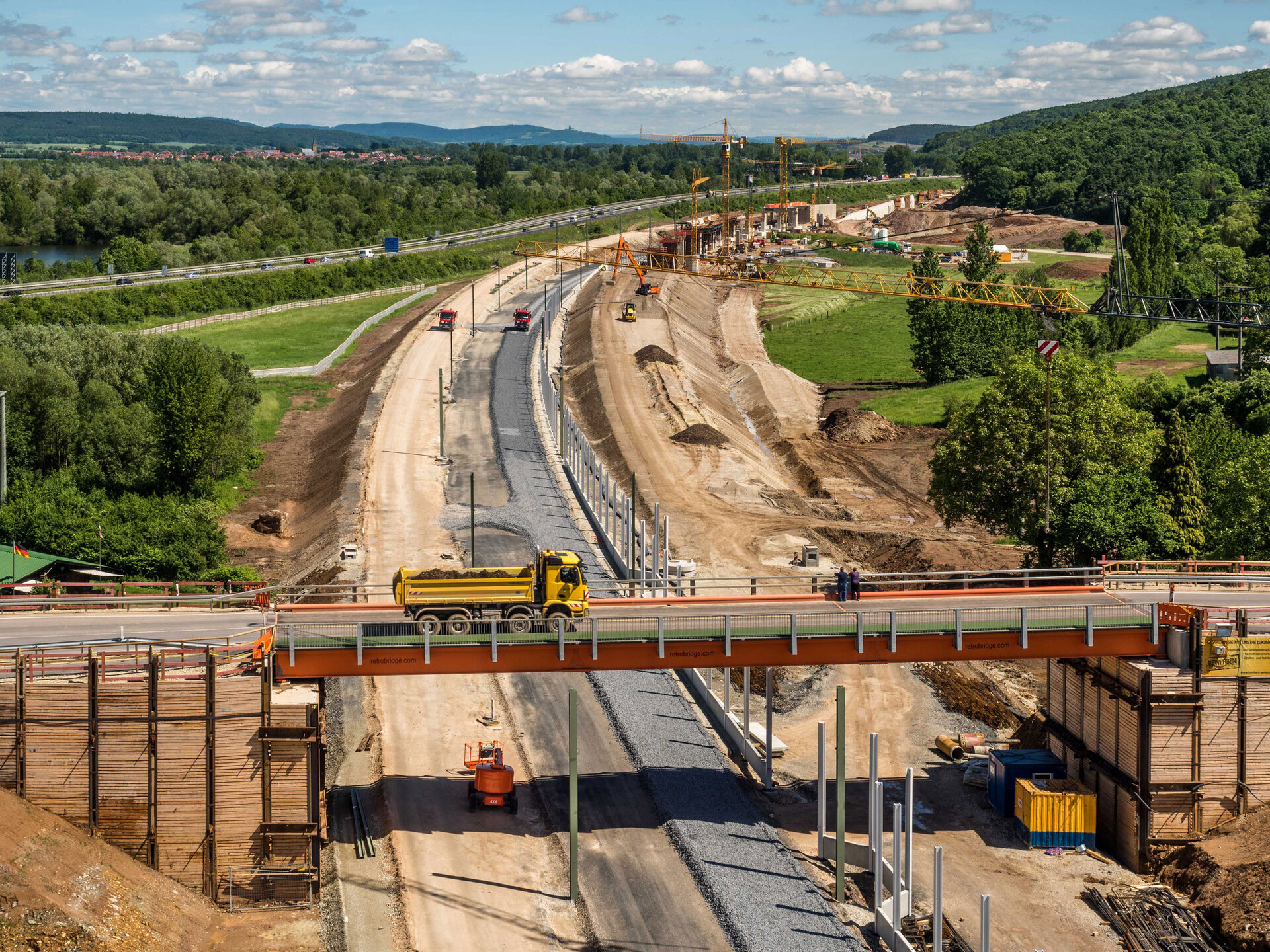 Baustelle in Zapfendorf mit einer Brücke, über die ein Lkw fährt, darunter Straßenbauarbeiten und grüne Landschaft im Hintergrund