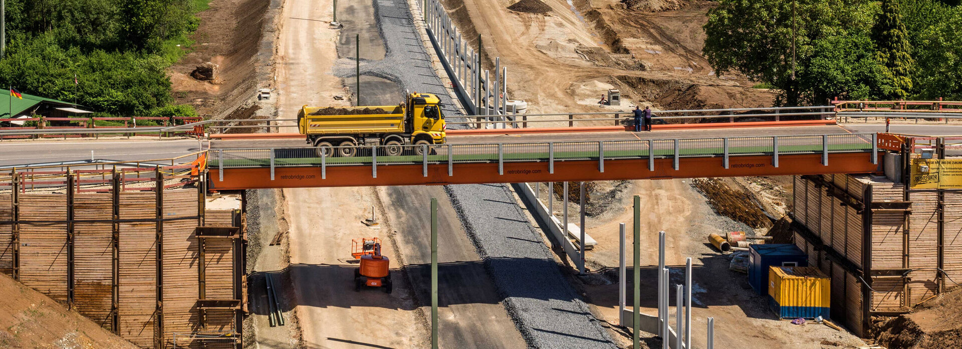 Baustelle in Zapfendorf mit einer Brücke, über die ein Lkw fährt, darunter Straßenbauarbeiten und grüne Landschaft im Hintergrund