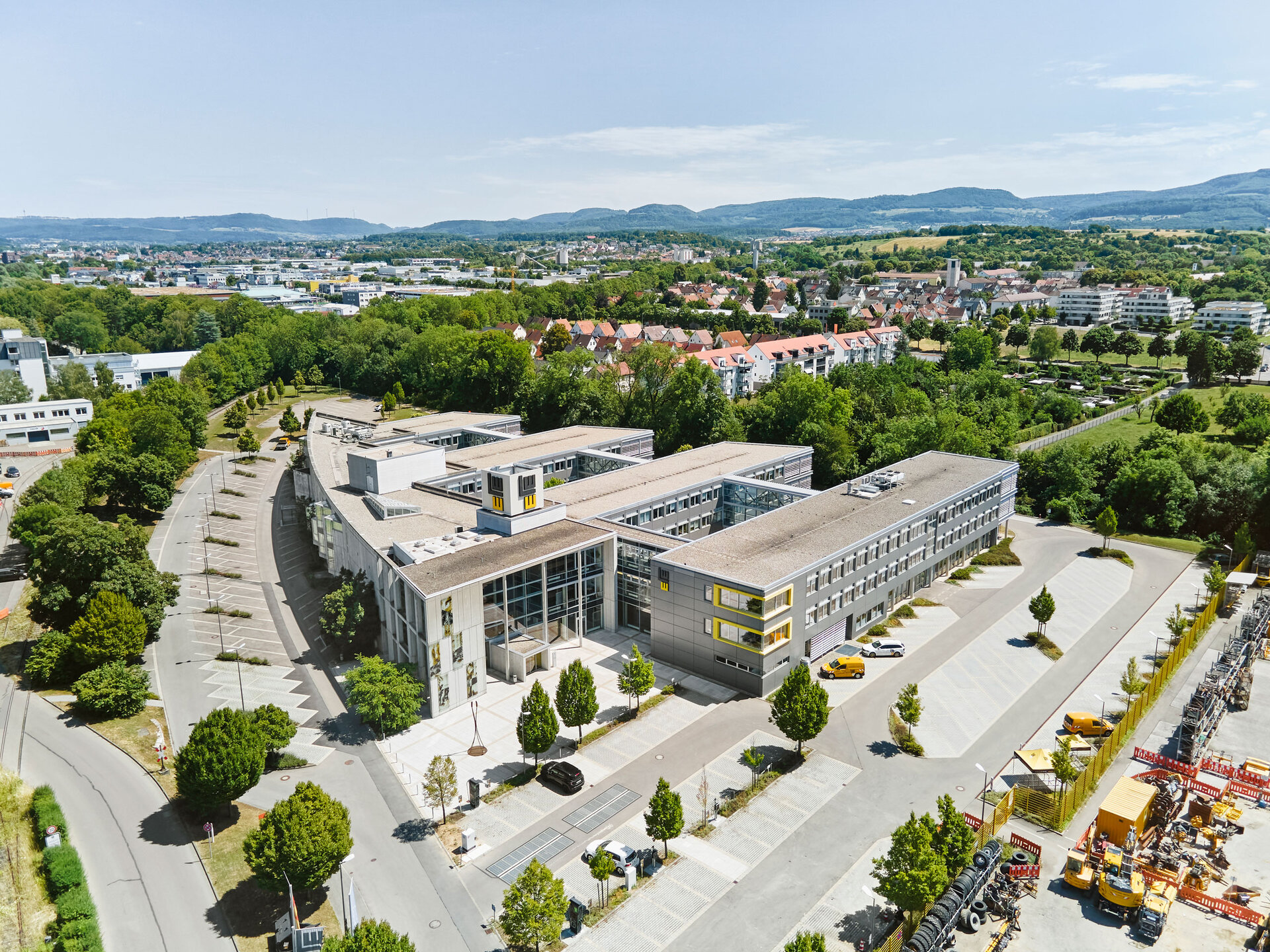 Luftaufnahme des LEONHARD WEISS Standorts in Göppingen mit weitläufigem Gelände, modernen Gebäuden, Parkplätzen und umliegender grüner Landschaft