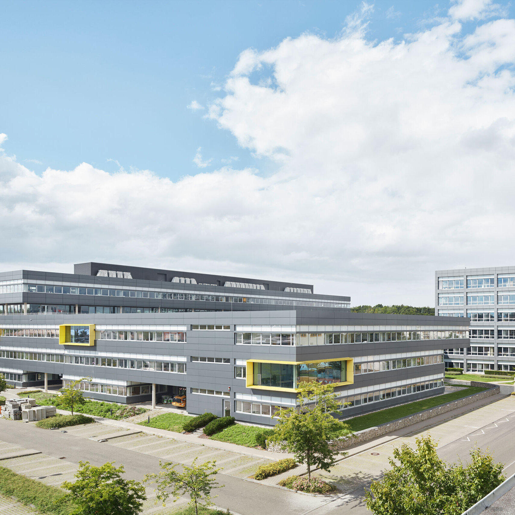 View of the LEONHARD WEISS site in Satteldorf with modern office buildings and landscaped grounds under a slightly cloudy sky