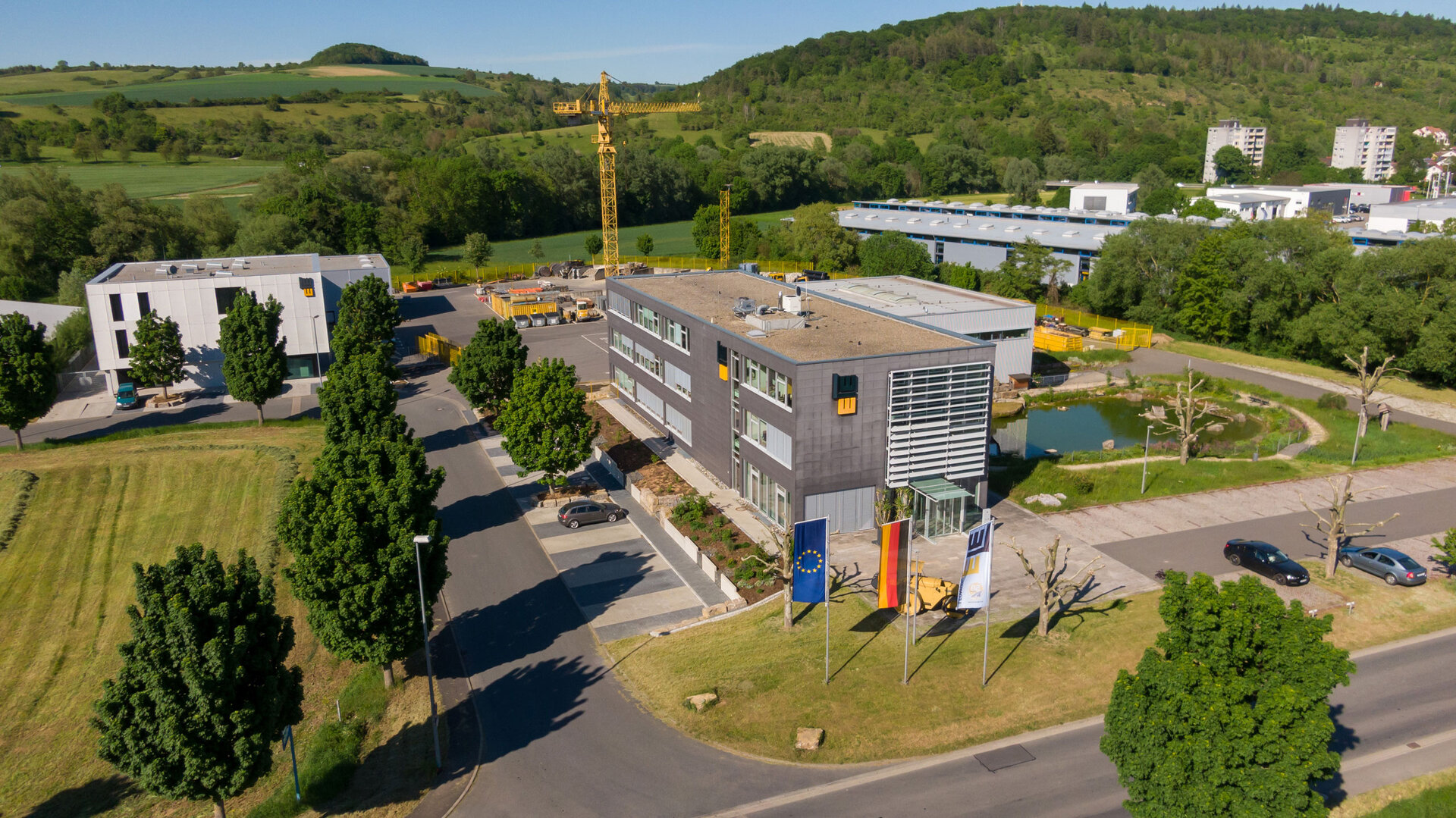 Luftaufnahme des LEONHARD WEISS Standorts in Bad Mergentheim. Bürogebäude umgeben von Grün und einem Teich