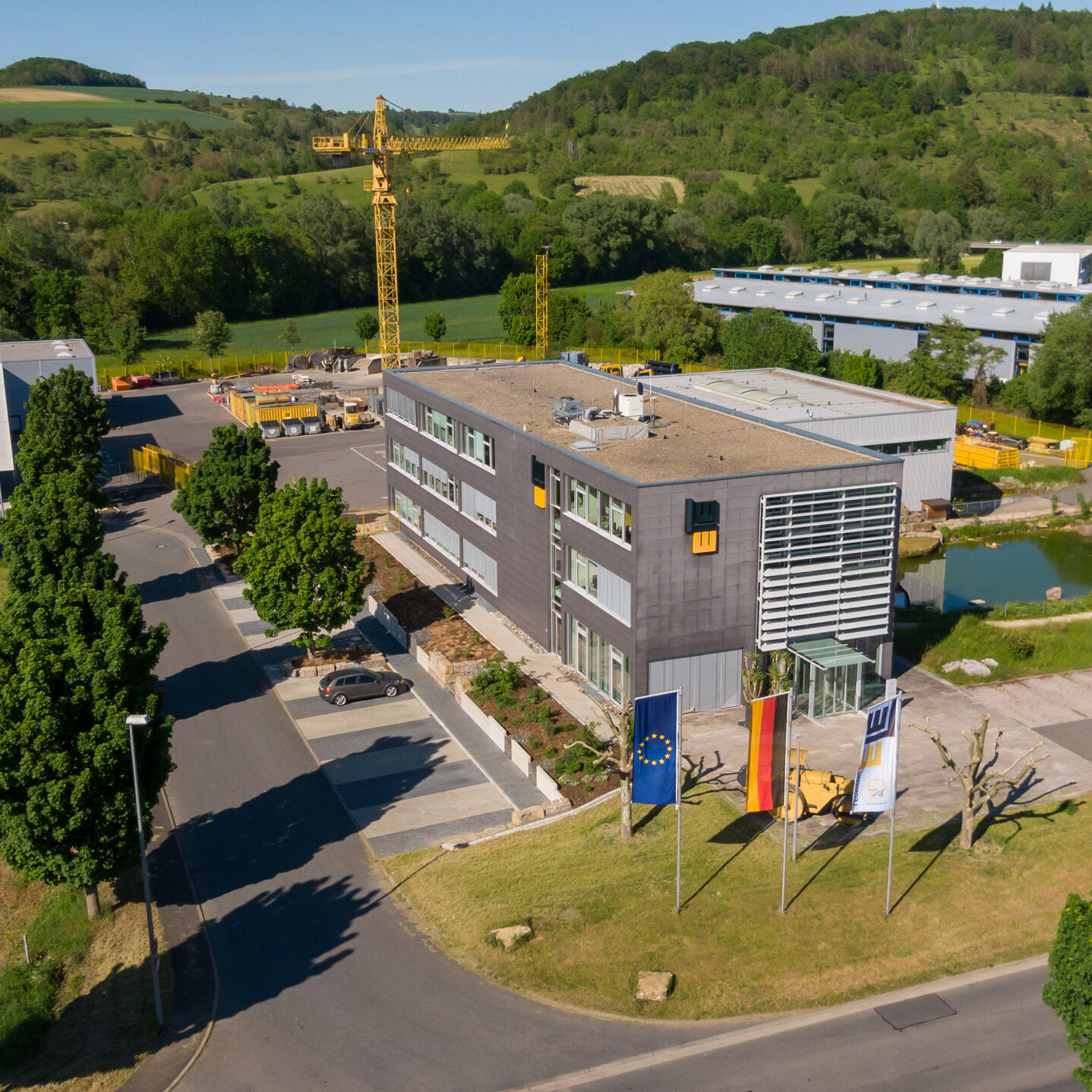 Aerial view of the LEONHARD WEISS site in Bad Mergentheim. Office building surrounded by greenery and a pond