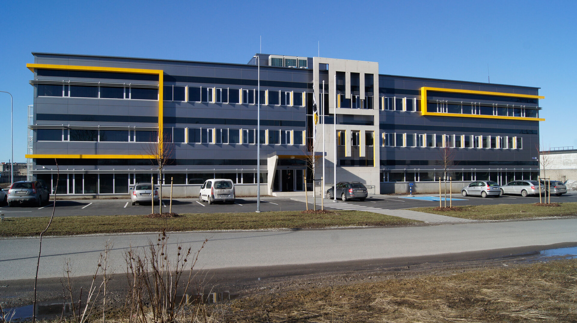 Bürogebäude von LEONHARD WEISS in Estland mit moderner Fassade, gelben Akzenten und geparkten Autos davor